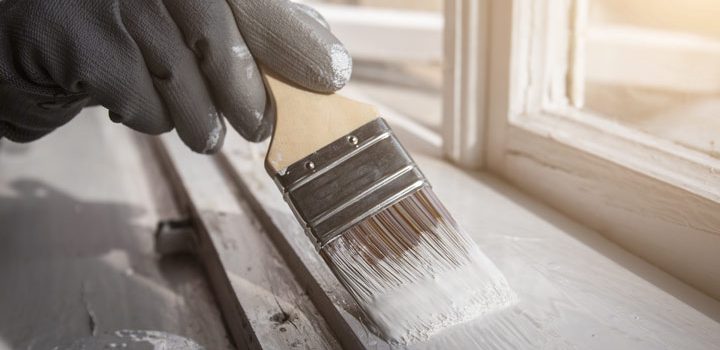 man painting the trim of the home in clean white color