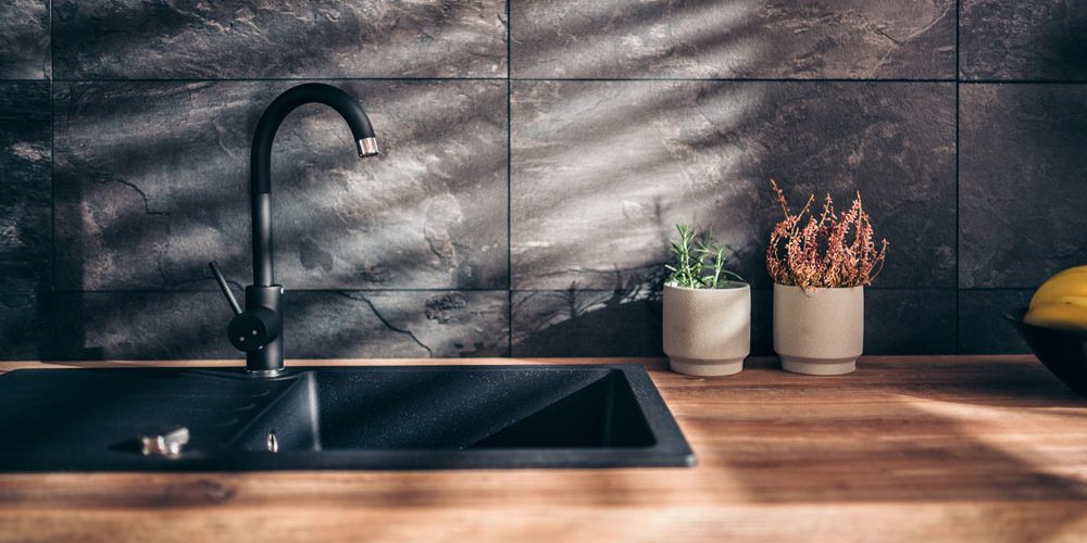black sink and kitchen faucet, paired with a stunning tile backsplash, make for a bold and striking statement in the newly renovated kitchen